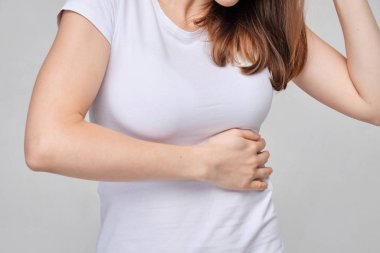 A girl in a white T-shirt massages the left side of the body from pain in the pancreas, spleen.