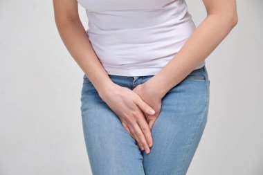 A girl in a white T-shirt massages the groin. Gynecology problems.