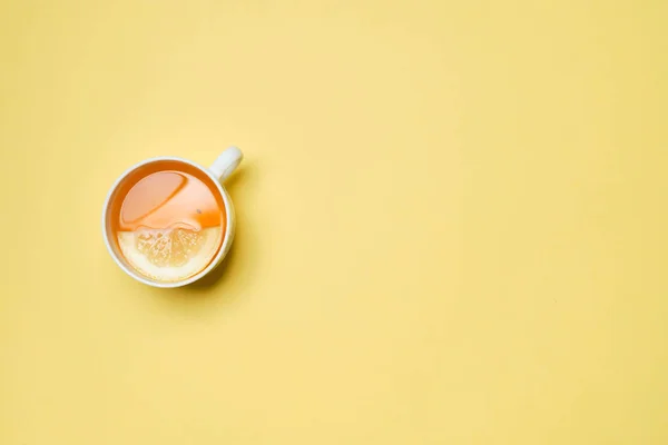 A cup of tea with lemon on a yellow paper background. Top view. — Stockfoto