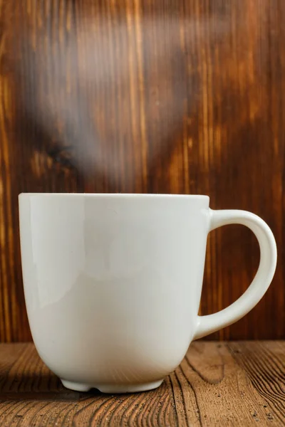 O ceașcă fierbinte de ceai cu abur peste ea pe un fundal de lemn ars . — Fotografie, imagine de stoc