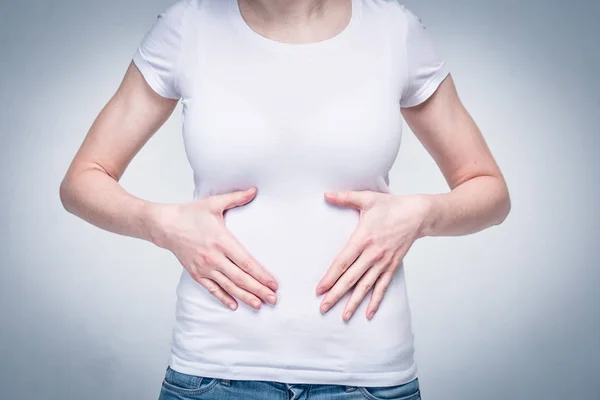 Retrato de uma menina em uma camiseta branca que sofre de dor no estômago e estômago devido à má alimentação e desnutrição. Tonificado . — Fotografia de Stock