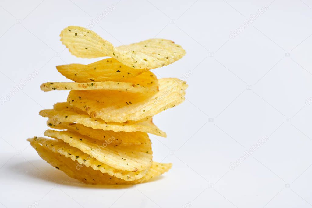 A vertical stack of potato chips with spices on a white background. Copy space.