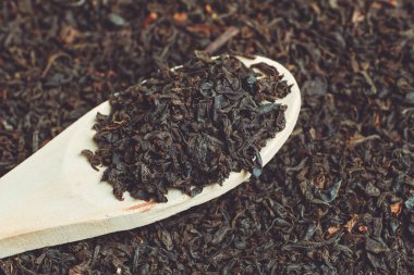 Wooden spoon on dry black tea. The concept of the distribution of tea by volume.