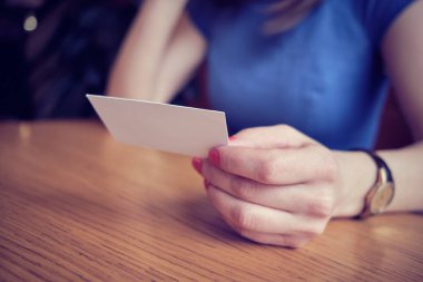 The girl in the cafe holds a business card. Concept of new design for your business.