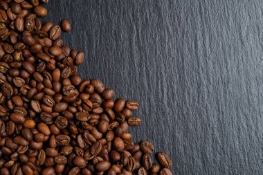 A lot of coffee beans laid out on slate with place for copy space. Top view.