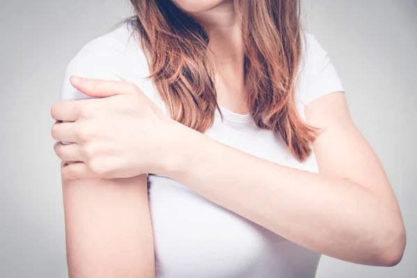 A girl in a white T-shirt massages her shoulder after an injection. Toned. — Stok fotoğraf