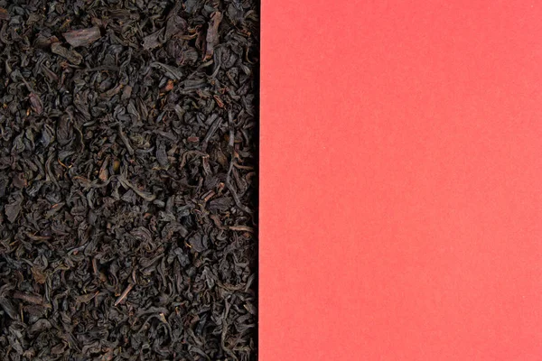 Red piece of paper on a background of dry scattered black tea with copy space. Top view. — Stock Fotó