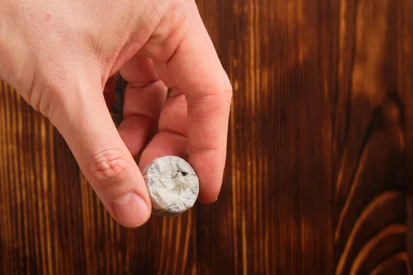 La mano de un hombre sostiene un manojo de té sobre un fondo de madera quemada . — Foto de Stock