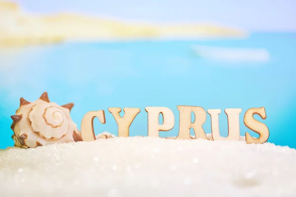 Abstract beach sand seashell on a blurred sea background with boat and letters. Cyprus is one of the most popular resorts in the world. — Stock Photo, Image