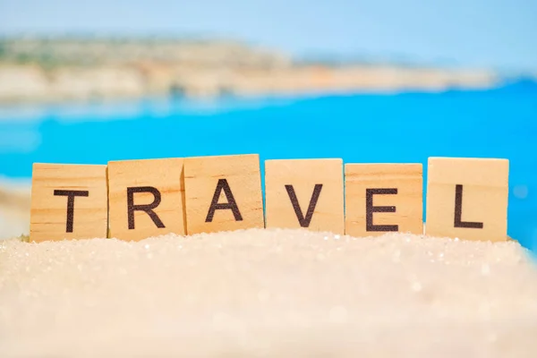 Abstract sand with letters on a background of blurred sea and mountains. Travel motivation concept. — Stockfoto
