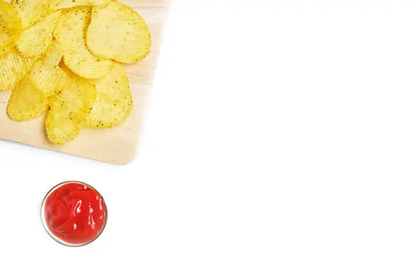 Chips on a wooden tray next to tomato ketchup in a bowl with copy space. Top view. — Stockfoto