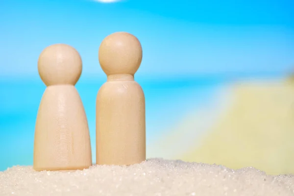 Abstract little men in the sand on a blurred beach background. Family vacation concept. Close up.