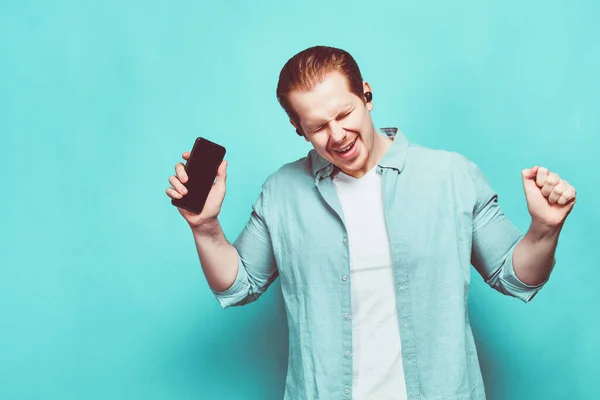 Ein Mann Legerer Kleidung Auf Blauem Grund Hält Ein Smartphone — Stockfoto