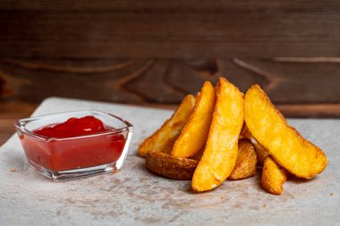 Kağıt üzerinde kızarmış patates ve ketçaplı ahşap arka plan. Kapat..