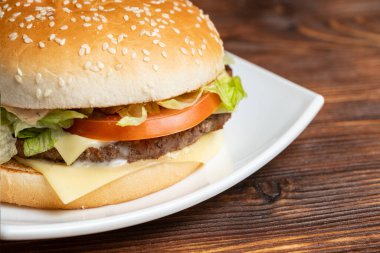 Beyaz tabakta hamburger ve büyüteçle ahşap bir arka plan. Kapat..