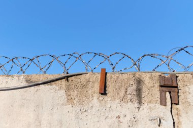 Mavi gökyüzü arka planlı dikenli hapishane duvarı. Kapat..