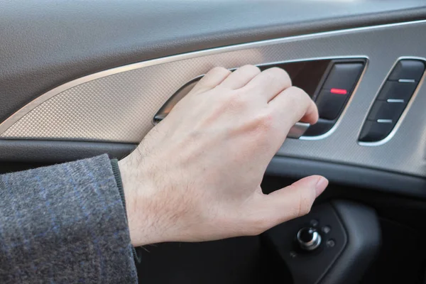 A man in a modern car. Hand pulls the lever to open the door. Close up.