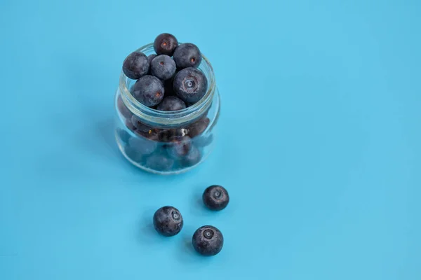 Botol Kaca Dengan Blueberry Latar Belakang Biru Tutup — Stok Foto