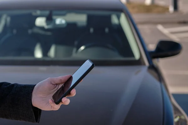 Ceketli Bir Adam Arabanın Arka Planında Akıllı Bir Telefon Tutuyor — Stok fotoğraf