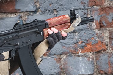 Kiralık asker, tuğla duvarın yanındaki modern bir tüfekten nişan alıyor. Kapat..