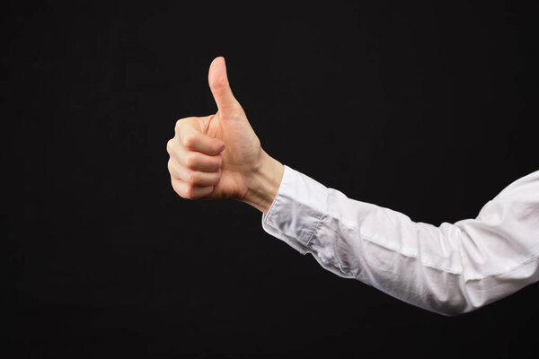 Caucasian businesswoman in a white shirt on a black background. Shows a gesture thumbs up. Close up. Copy space.
