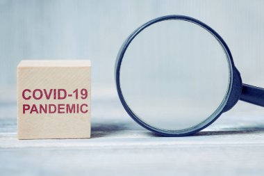 Üzerinde yazıt virüsü olan tahta bloklar, COVID-19 PANDEMIC, büyüteçin yanında. Kapat..