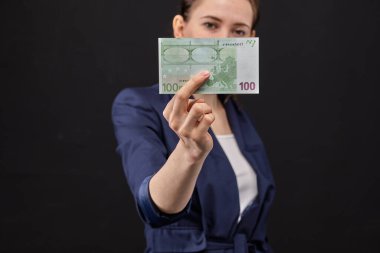 Siyah arka planda Avro banknotu tutan ceketli bir kız. Kapat..