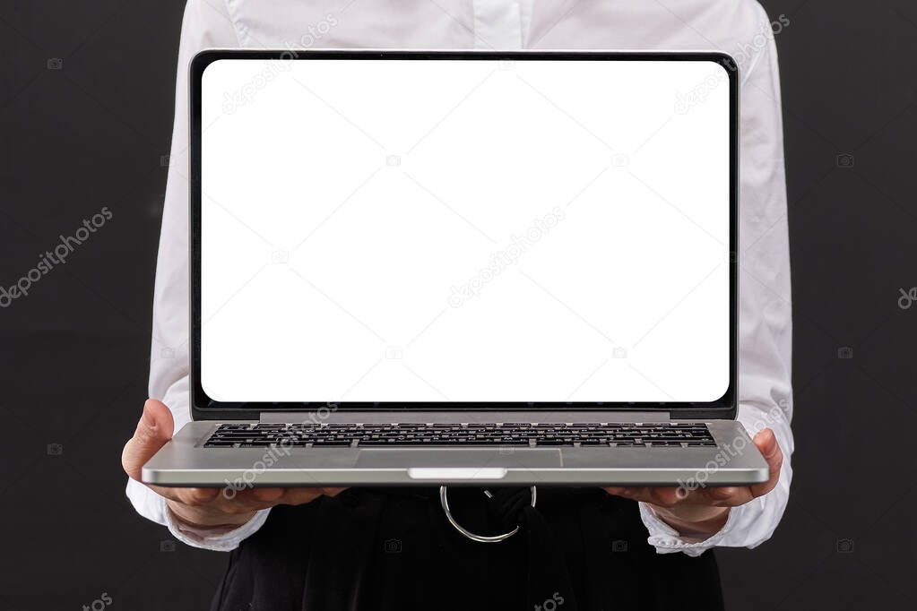 Girl in a white shirt holding a laptop with copy space on a black background. Close up.
