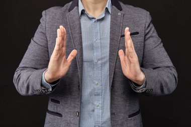 Ceketli bir adam elleriyle soyut bir nesne gösteriyor. Kapat..