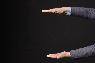 Ceketli bir adam siyah arka planda avucunun içinde bir nesne tutuyor. Kapat..