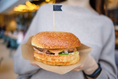 Masada hamburgerler ve çatalını ve bıçağını yiyen bir kız. Kapat..