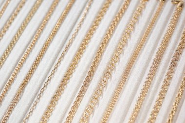 Beyaz tezgahta altın zincirler ve mücevherler. Kapat..