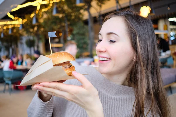 Girl Holds Burger Her Hands Looks Him Close — Stock Photo, Image