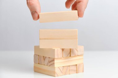 El, beyaz arka planda üç tahta bloğu tutuyor. Uzayı kopyala Kapat..