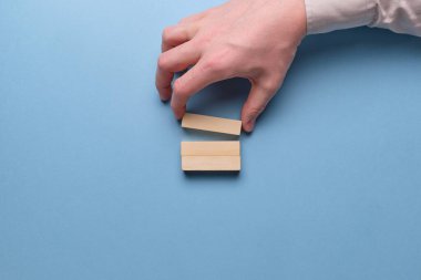 Yeni iş fikirleri kavramı. Mavi arka planda ahşap blokları tutan eller. Kapat..