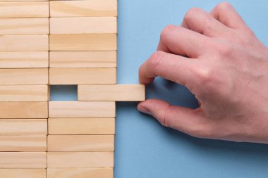 İş cirosundan para çekme konsepti. Mavi arka planda ahşap blokları tutan eller. Kapat..