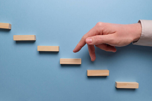 Action plan concept. Hand holds wooden blocks on a blue background. Close up.