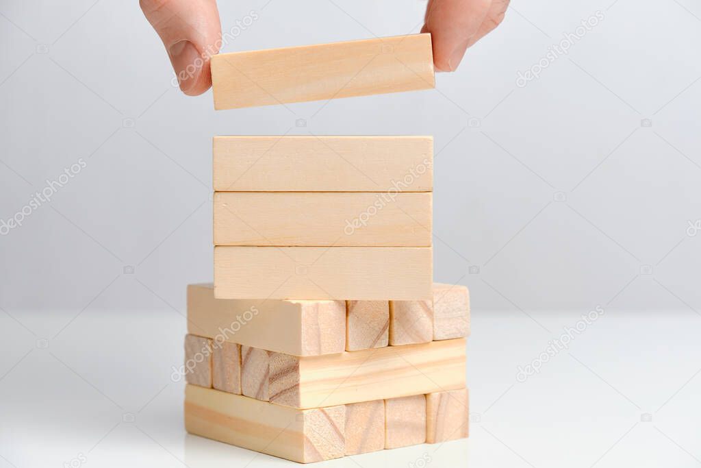 Hand holds four wooden blocks on a white background. Copy space. Close up.