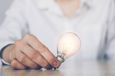 Yaratıcılık kavramı ve iş dünyasındaki fikirler - el bir ampul tutar. Kapat..
