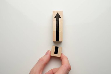 Yaratıcı ve iş geliştirme konsepti: Kara oklu ahşap küpü tutan el. Kapat..