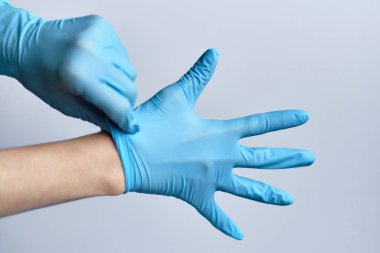 Mavi tıbbi eldivenleri beyaz arka plana koyma süreci. Kapat..