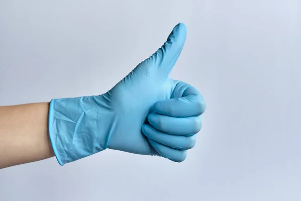 在白色背景上戴着蓝色医疗手套的手显示一个大拇指像 — 图库照片