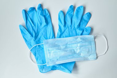 Beyaz arka planda tıbbi maske ve koruyucu eldivenler. Kapat..