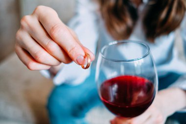 Kadının elinde bir bardak şarabın yanında alyans var. Boşanma kavramı. Kapat..