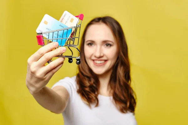 Girl Holds Credit Cards Shopping Trolley Yellow Background Close — Stock Photo, Image