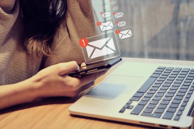 Kafedeki bir kız bilgisayarında akıllı telefon tutuyor ve e-postasında yeni bir mesaj simgesi var. Kapat..