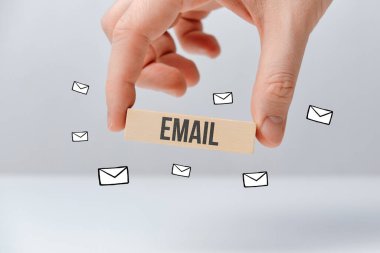 Elleri ahşap blokta, içinde zarf simgeleri olan bir e-posta tutuyor. Kapat..