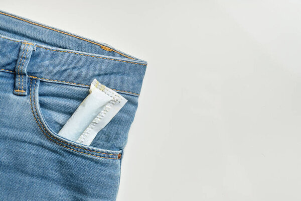 Female tampon in a pocket of blue jeans with copy space on a white background. Close up.