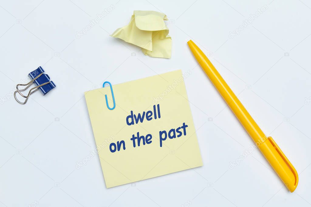 English idiom hand lettering about time - dwell on the past on wooden blocks. Close up.