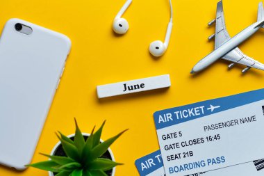 Uçak ve biletlerle haziran yolculuğu konsepti, üst görüşlü sarı arka planda akıllı telefon..